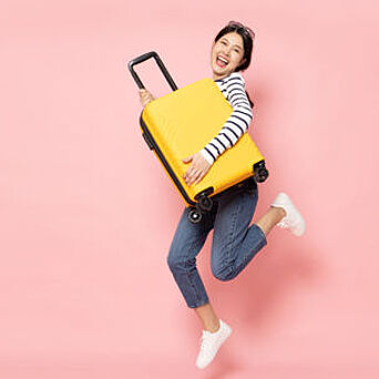 Woman holding yellow, hard-sided luggage