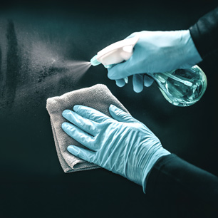 Close-up of gloved hands inspecting material surface after disinfectant exposure using lab tools