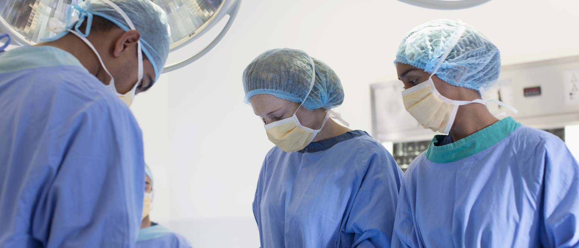 Group of surgeons wearing face masks and sterile gowns in an operating room