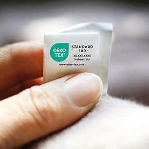 Hand holding up a textile with OEKO-TEX® STANDARD 100 sew-in label