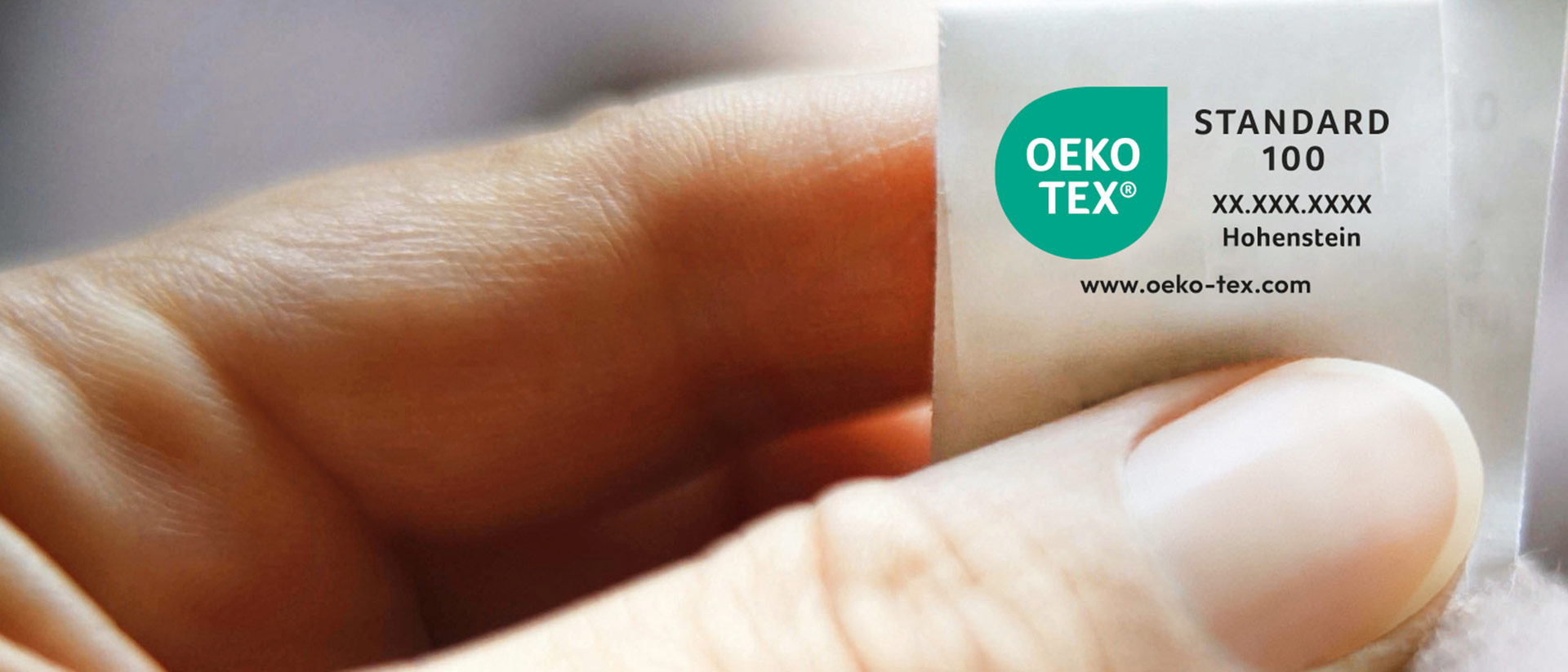 Hand holding a textile with OEKO-TEX® STANDARD 100 sew-in label