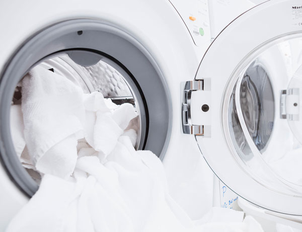 Testing the Washability of Textiles Home laundry machine with door open and white linens