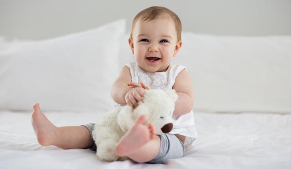Ensuring Safe, High Quality, Compliant Toys Baby holding stuffed animal on bed